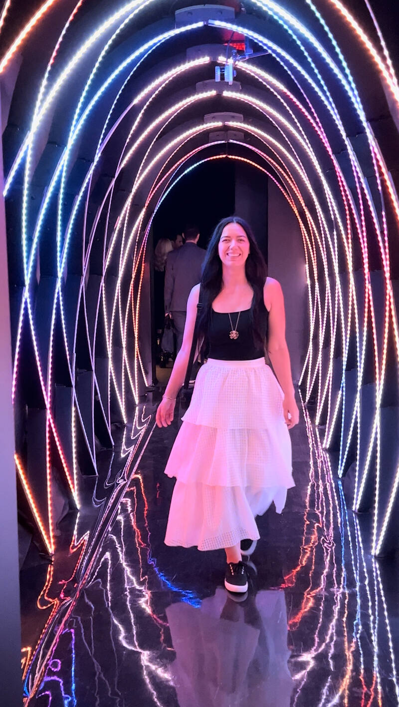 A woman walking through a tunnel of colorful lights