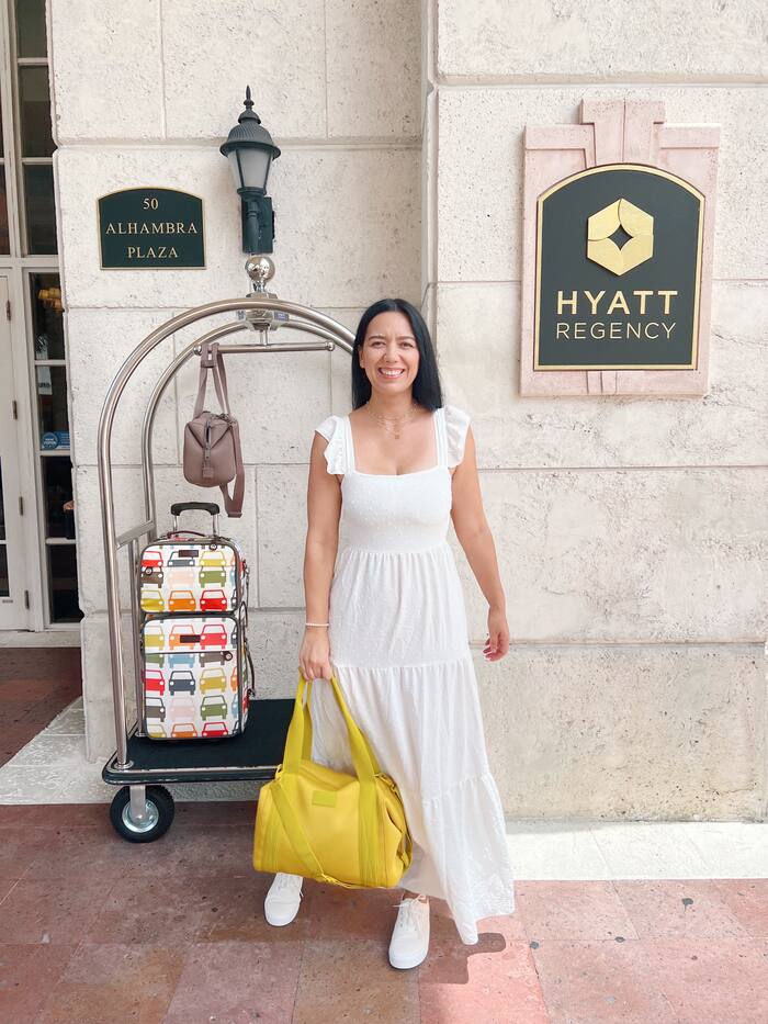 Paola Mendez in a white dress at a hotel entrance