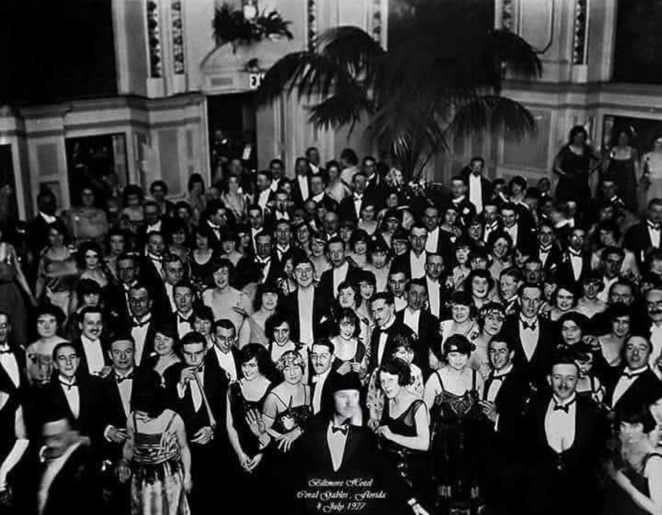 Crowd of 1920s partygoers in black tie and flapper dresses in a ballroom, captioned Biltmore Hotel Coral Gables Florida 4 July 1927