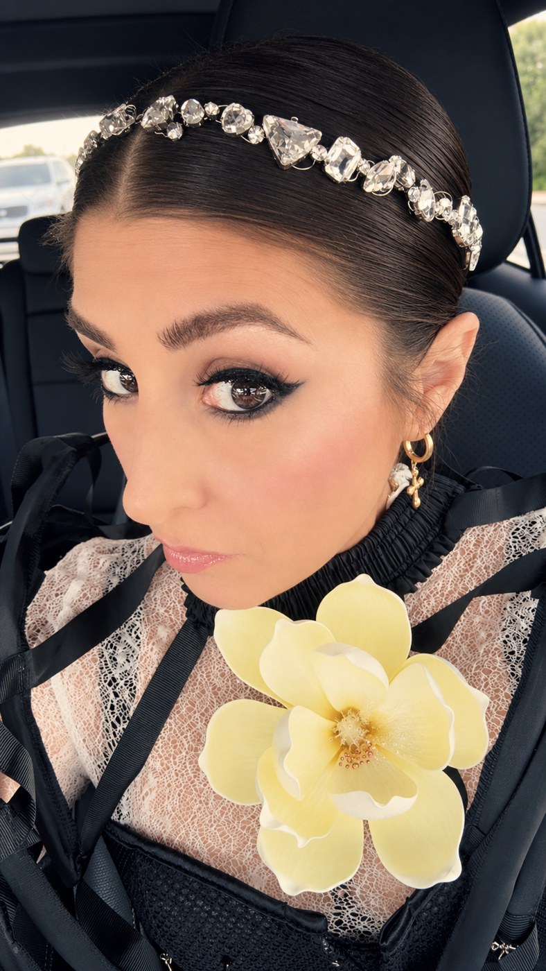 Asha Lloret in a crystal headpiece, winged liner, cross earring and a yellow magnolia on lace